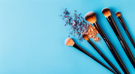 Set of makeup brushes with scattered eyeshadow on a blue background. Beauty tools for cosmetics application, showcasing different brush types and vibrant makeup colors.