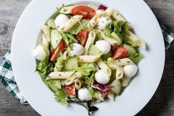 Pasta salad with vegetables and mozzarella cheese on wooden table. Close up