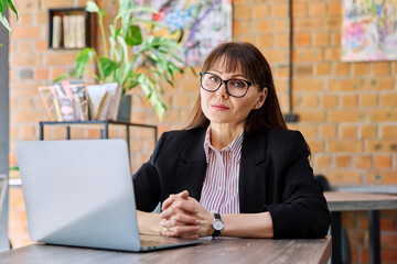 Middle-aged business woman working remotely with laptop in coworking