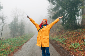 Amidst the fall foliage, a young woman explores the national park, hiking along a foggy walkway and...