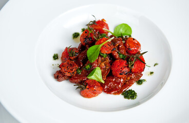 Gourmet roasted cherry tomatoes garnished with herbs on a white plate