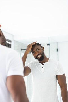 At home, African American man checking his hair in mirror