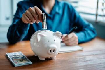 woman hand putting dollar bills into piggy bank for planning saving money wealth to planning...