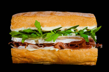 Gourmet turkey and arugula sandwich on black background