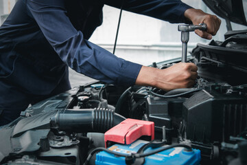 Mechanic using wrench while working on car engine outside the service center , Repair and service.