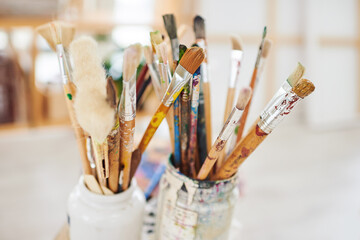Paintbrush, art and tools for creativity in studio, color and craft in small business and shop. Workshop, equipment and supplies in jars or container for project, decoration and production in store