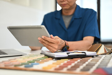 Senior male decorator or interior designer drawing a sketch on a digital tablet at desk