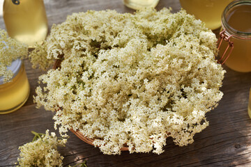Fresh elderberry flowers in a basket with homemade herbal syrup