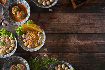Top view of various spicy Thai noodles, scalded meatball and vegetables on wooden table