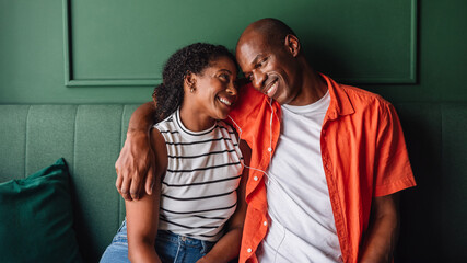 Obraz premium Happy couple sharing a joyful moment on a green sofa