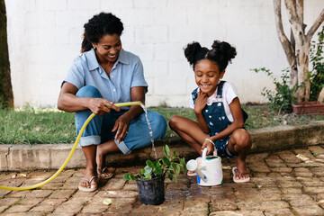 Mother and daughter watering plants together on a sunny day