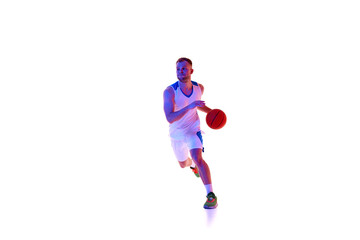 Basketball player in motion, running forward and training dribbling technique in neon light against white studio background. Concept of professional sport, games, healthy lifestyle, tournament, action