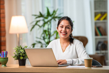 Indian asian young beautiful female business woman working on laptop on table or desk