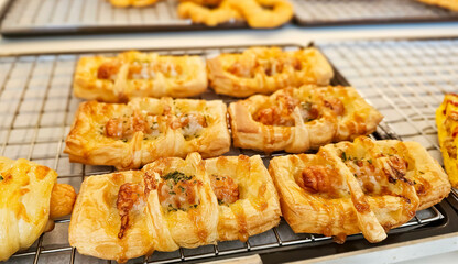 Savory crescent rolls with cheese with sausage filling. Fresh French Bread and croissants in a bakers rack. Freshly baked sausage pie on bakery shelf for sell.