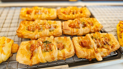 Savory crescent rolls with cheese with sausage filling. Fresh French Bread and croissants in a bakers rack. Freshly baked sausage pie on bakery shelf for sell.