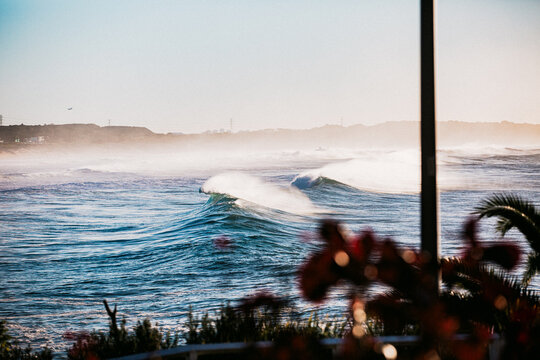 Waves crashing coastline at sunrise with sea spray