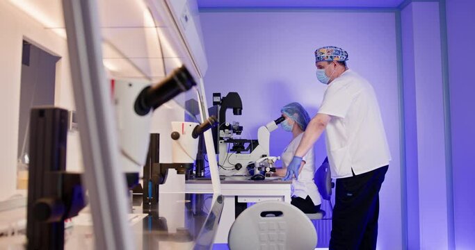 Embryologists performing in vitro fertilization procedures in a modern laboratory setting with specialized equipment. Scientific expertise in reproductive technology. IVF process in action.