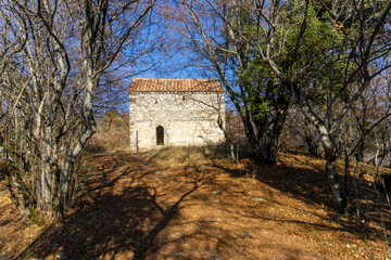 Obraz premium Small church on the woods. Tiled roof, stone wall and entrance. Autumn view and colors.