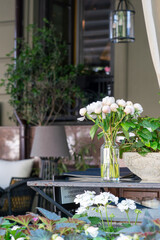 A bouquet of white peonies stands on the outdoor reception table. The concept of a summer terrace of a fine restaurant in spring or summer.
