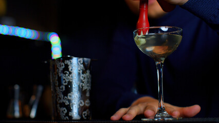 A professional bartender preparing an alcoholic cocktail with cream topping. Media. Making a...