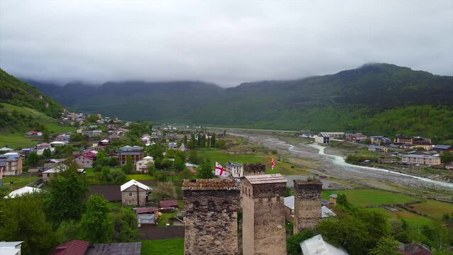 tunning aerial shot of ancient Georgian towers nestled amidst a scenic mountain landscape. Lush green valleys and a flowing river add to the beauty of this historical site