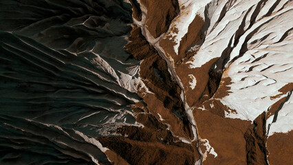Aerial top view of the mysterious mountain rocks. Clip. White stone layers and brown ground.