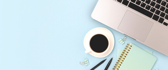Stationery, laptop and cup of coffee on a blue background. Banner with copy space.