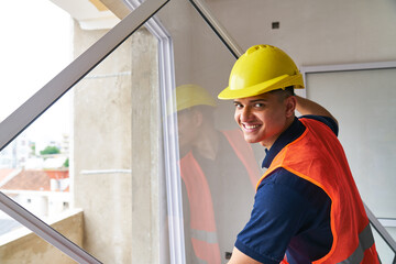 Portrait of smiling young male carpenter installing window frame at incomplete house