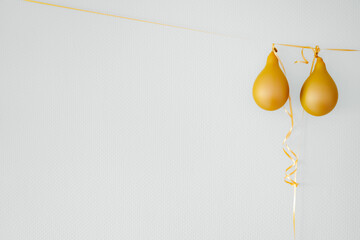 Deflated yellow balloons on golden string white background. After party holiday concept