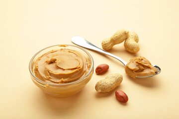Bowl of peanut butter and peanuts on beige background. Creamy peanut pasta in small bowl.