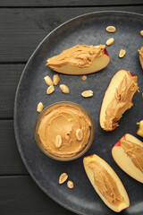 Slices of fresh apple with peanut butter and nuts on dark background.