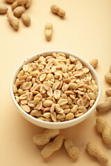 Roasted peanuts on white bowl on beige background