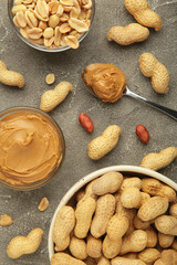 Bowl of peanut butter and peanuts on grey concrete background. Creamy peanut pasta in small bowl.