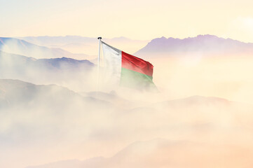 Madagascar flag disappears in beautiful clouds with fog.