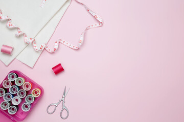 Composition with various threads and sewing accessories on pink background. Top view, copy space