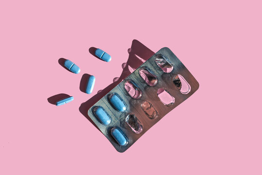 Blue pills and blister pack over pink background