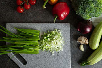 Green onions cut on chopping board surrounded with fresh ingredients for food preparation