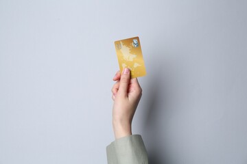 Woman holding credit card on light grey background, closeup