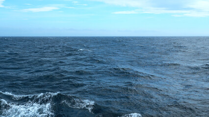Naklejka premium Beautiful view of horizon of blue sea with waves. Clip. Foam from waves in blue sea. In blue sea with waves on background horizon with blue sky