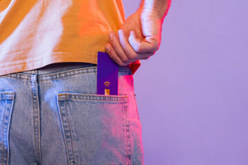 Cropped of man is shown holding a purple card and placing it inside their pocket. The individuals...