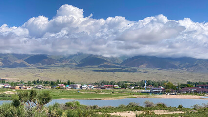 Beautiful summer mountain landscape. View of the mountain range with a small town in the valley below. Travel to Kyrgyzstan