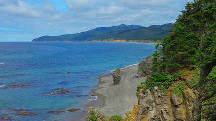 Beautiful view of bend of coast with rocks on sunny day. Clip. Landscape of rocky coast with green...