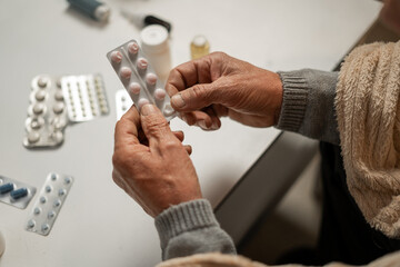 Close-up of the hands of an elderly man holding pills and medicines in his hands. Medicine and...