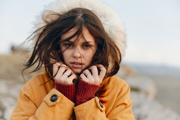 Fashionable woman in yellow jacket and gloves posing with hands on face for camera beauty and style portrait