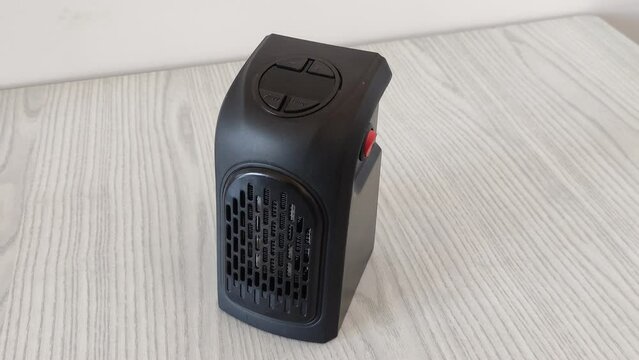 Black electric mini air heater for room on the wooden table