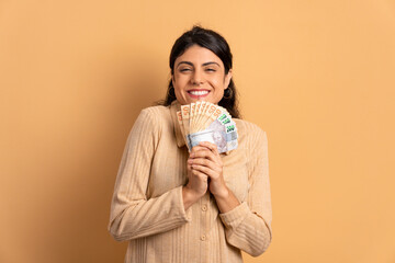 happy brazilian woman celebrating successful business money in beige colors. economy, payment,...