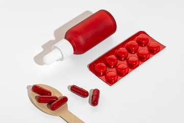 A dropper bottle of face serum and vitamin capsules and pills