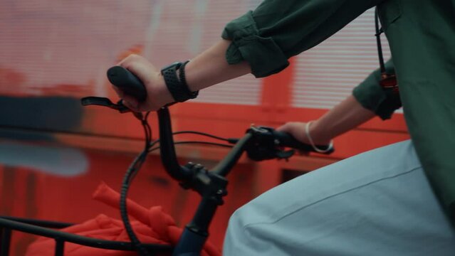 Close up on woman cycling on small compact electric bicycle in city. E-bike rider on a bike lane. Cargo bicycle with transportation basket in front. Urban transportation and modern mobility