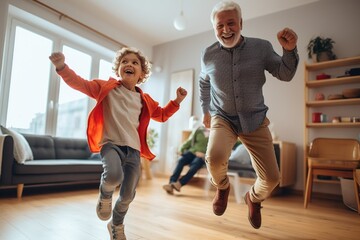 Cute little boy grandson having fun dancing with old elderly grandpa in living room, happy two generation active family senior grandfather and small grandchild playing enjoying time together at home.