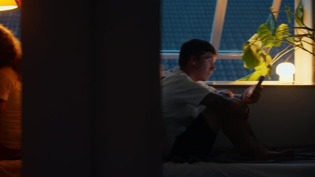 Modern broken couple, distant from each other sit in separate rooms on their devices. Man and woman after an argument, distanced and emotionless, after dispute or disagreement on screen time
